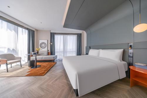a bedroom with a large white bed and a living room at Atour S Hotel Chongqing Yubei Central Park in Yubei