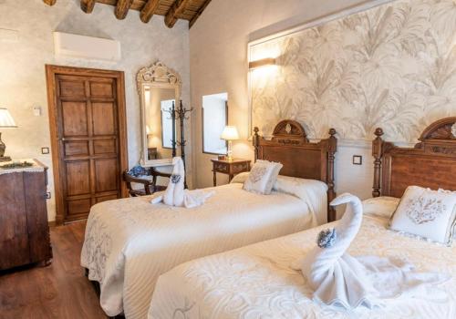 a bedroom with two beds with white sheets at Casa Rural El Baluarte Habitaciones in Caudilla