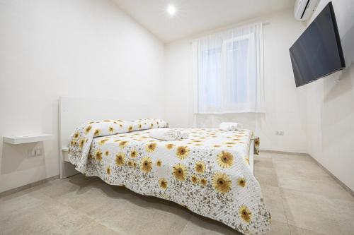 a white bedroom with a bed with a floral bedspread at Villa Lumia in Tre Fontane