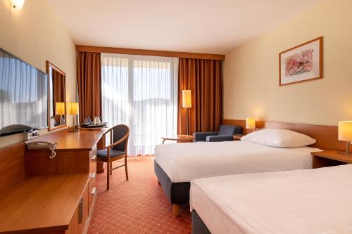 a hotel room with two beds and a desk at Mercure Karpacz Skalny in Karpacz