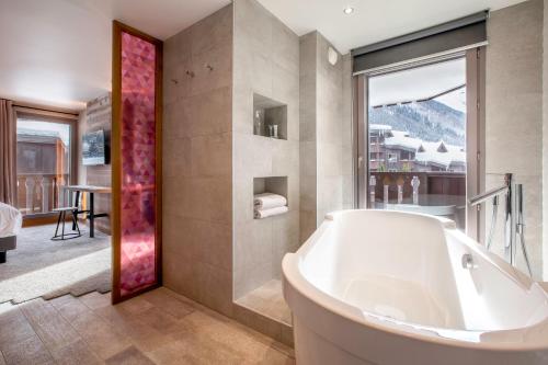 a bathroom with a tub and a large window at Lykke Hôtel & Spa Chamonix - ex Mercure in Chamonix-Mont-Blanc