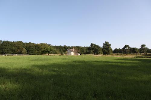 a large green field with a house in the distance at Gîte d'Aigues Vives in Céré-la-Ronde