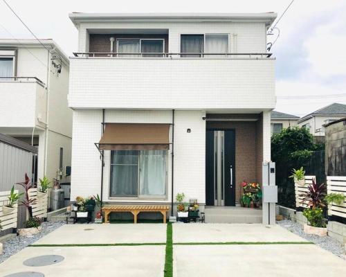 a white house with a bench in front of it at "包棟首選" - 沖繩讀谷4房獨棟別墅 - 最多10人 - 家庭友善 - 價錢已包括4位旅客 in Yomitan