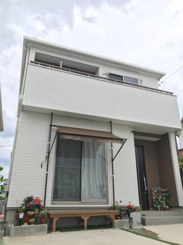 a white house with a window and flowers in front at "包棟首選" - 沖繩讀谷4房獨棟別墅 - 最多10人 - 家庭友善 - 價錢已包括4位旅客 in Yomitan