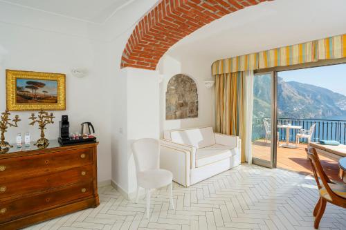 a living room with a chair and a dresser and a balcony at Hotel Le Agavi in Positano