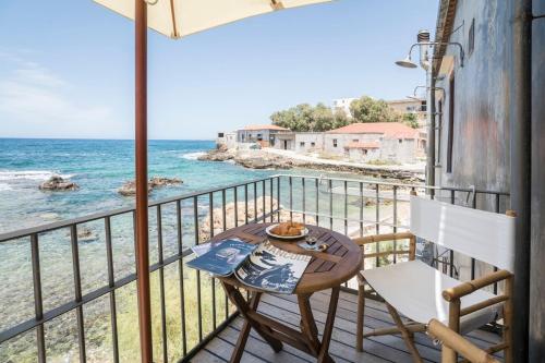 a balcony with a table and chairs and the ocean at kito- transformed house on the water's edge in Chania