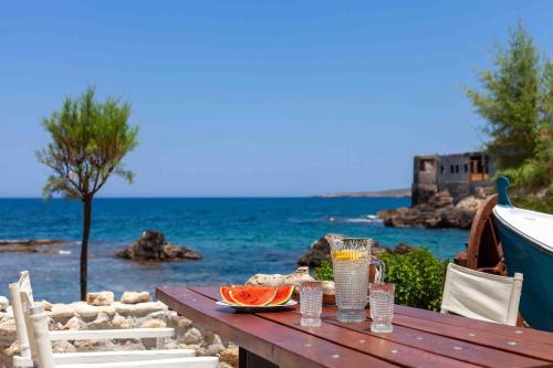 una mesa de picnic con un plato de comida en la playa en Skiff - Transformed studio on the water's edge, en La Canea