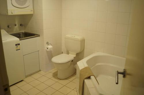 a bathroom with a toilet and a sink and a tub at Vail next to coffee mecca in Canberra