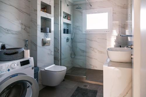 a bathroom with a toilet a sink and a washing machine at Christinas apartment in Nea Moudania