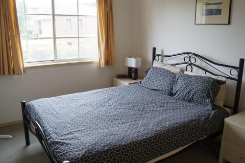 a bedroom with a bed with blue sheets and a window at Vail next to coffee mecca in Canberra