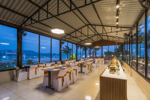 a restaurant with tables and chairs and large windows at RiverView Tent Resort in Kevadia