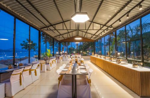 a restaurant with tables and chairs and large windows at RiverView Tent Resort in Kevadia