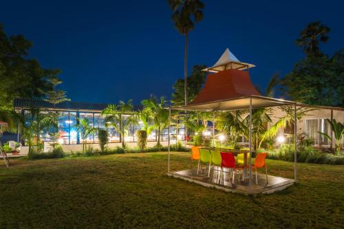 a table with chairs under a large umbrella at RiverView Tent Resort in Kevadia