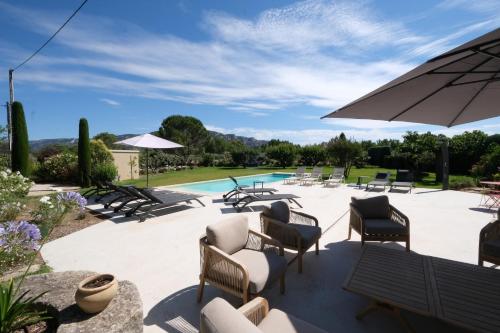 une terrasse avec des chaises et un parasol ainsi qu'une piscine dans l'établissement provencal house with heated pool, view of the luberon in robion - accommodates 12 people., à Robion