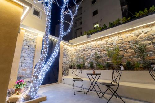 eine Terrasse mit 2 Stühlen und einem Baum mit Licht in der Unterkunft Industrial - Le Petit Bati in Volos