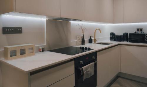 a white kitchen with a sink and a stove at Luxurious Apartment in St Albans in St. Albans