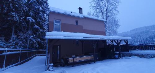 a house with snow on the roof in front of it at Lipno & Wellness Chata in Loučovice