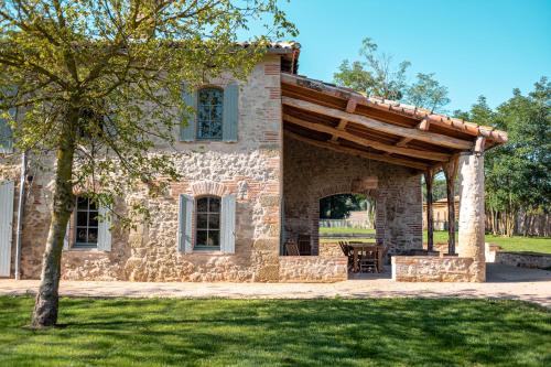 a stone house with a wooden pergola at Chambre tout confort à l'Héritier - au coeur du Tarn in Marzens