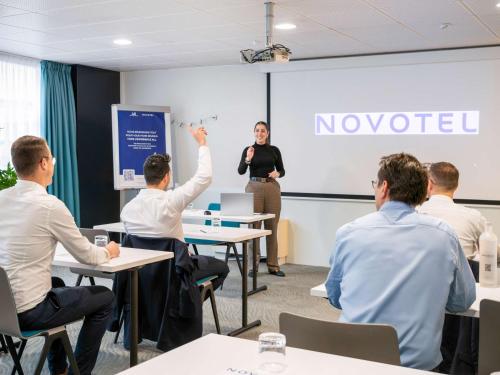 Un groupe de personnes dans une salle de classe où une femme fait une présentation dans l'établissement Novotel Grenoble Centre, à Grenoble