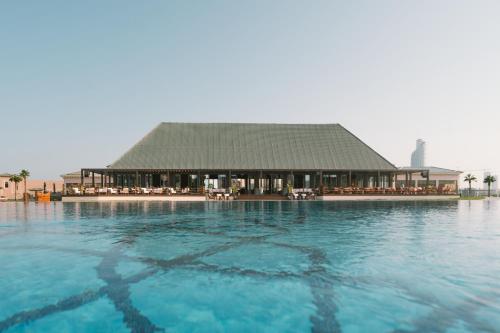 a swimming pool with a building in the water at Royal Saray Resort in Manama