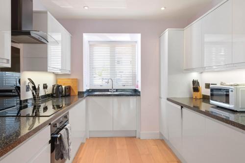 a white kitchen with a sink and a microwave at Townhouse Parking 1 Min Walk to Tolcarne Beach in Newquay
