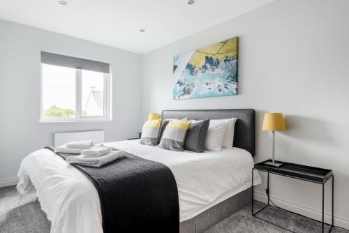 a bedroom with a large white bed and a window at Modern House in St Agnes Parking & Garden in St. Agnes