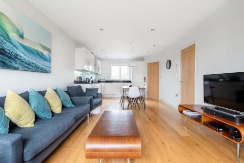 a living room with a blue couch and a table at Modern House in St Agnes Parking & Garden in St. Agnes