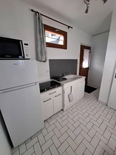 La cuisine blanche est équipée d'un évier et d'un réfrigérateur. dans l'établissement le gîte de Gabriel - studio, à Saint-Martin-dʼAblois