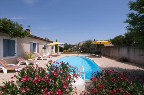 une piscine avec chaises et parasols dans une cour dans l'établissement pretty holiday rental with swimming pool in isle-sur-la-sorgue, in the département of vaucluse, in provence 4 people, à LʼIsle-sur-la-Sorgue