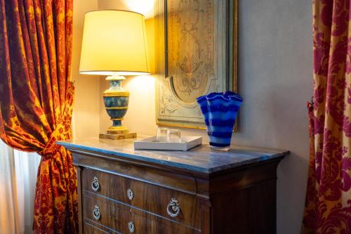a lamp on a dresser with a blue vase on it at Foresteria del Castello di San Giorgio Canavese in San Giorgio Canavese