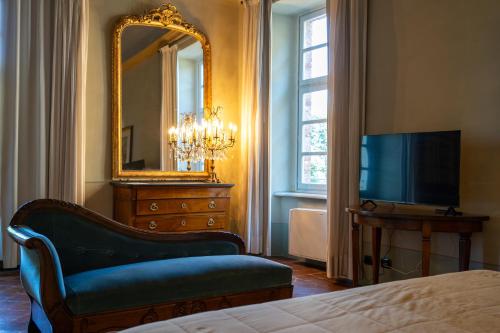 a bedroom with a mirror and a chair and a tv at Foresteria del Castello di San Giorgio Canavese in San Giorgio Canavese