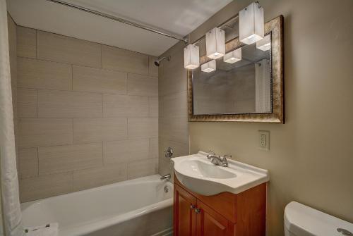 bagno con lavandino, vasca e specchio di The Putney Inn a Putney