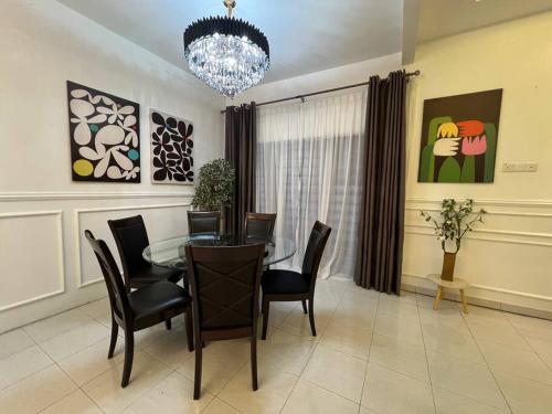 a dining room with a glass table and chairs at Rumah Cemara by Impian Homestay in Sepang