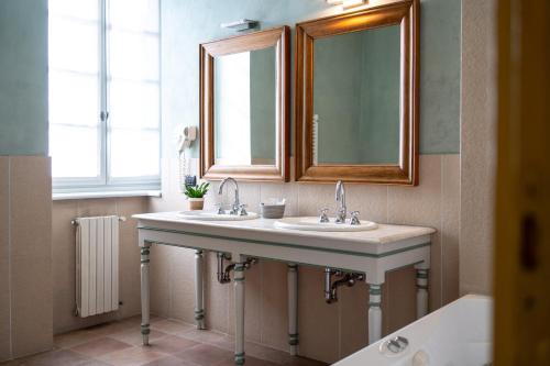 a bathroom with two sinks and a mirror and a tub at Foresteria del Castello di San Giorgio Canavese in San Giorgio Canavese