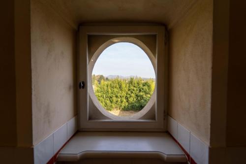 anorthole window in a room with a view of trees at Foresteria del Castello di San Giorgio Canavese in San Giorgio Canavese
