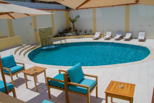 a pool in a hotel room with chairs and a table at Hotel Maresta Lodge - Hotel Asociado Casa Andina in Chimbote