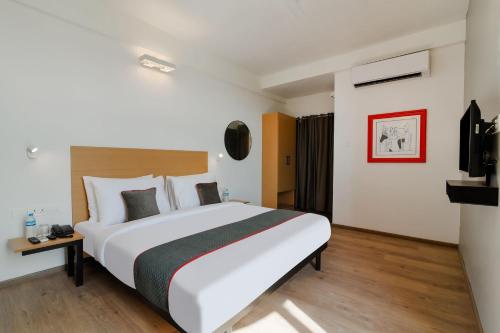 a hotel room with a large bed and a tv at Super Townhouse Srm Kuppakonam Pudur in Coimbatore