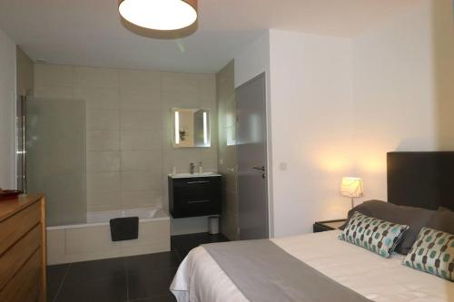a bedroom with a bed and a bathroom with a sink at Maison basque moderne avec piscine chauffée et vue in Ascain