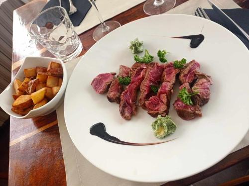a white plate with meat and broccoli and a bowl of potatoes at Hôtel Les Fleurs in Pontaubert