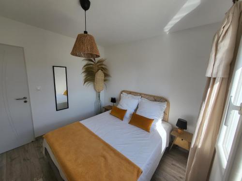 a bedroom with a bed with white sheets and orange pillows at Pleasant detached villa with private swimming pool for 6 people in Lauris - Luberon. in Lauris