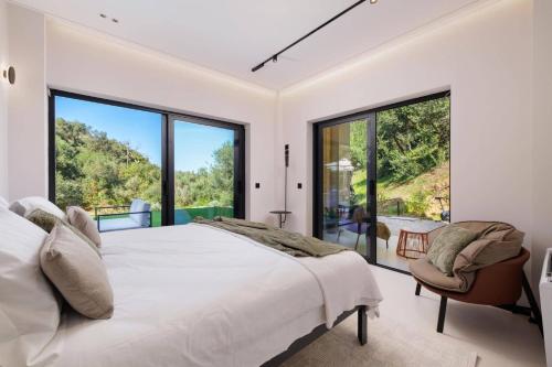 a bedroom with a large bed and large windows at Villa Optima by Villa Plus in Peroúlion