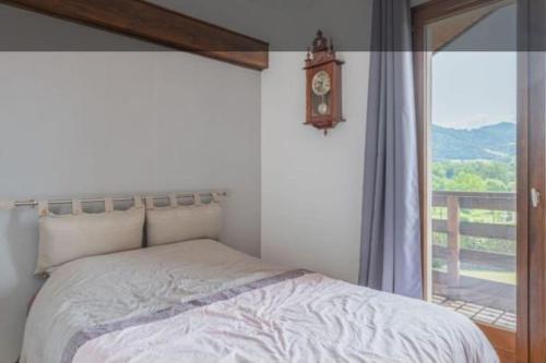 - une chambre avec un lit et une fenêtre avec une horloge dans l'établissement Magnifique VILLA Piscine chauffée ouverte Vue Montagne prêt Genêve et Chamonix, à Ville-en-Sallaz