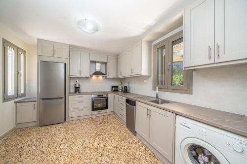 a kitchen with white cabinets and a washer at Villa Onera in Vlachata