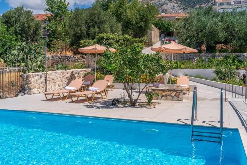a swimming pool with chairs and umbrellas next to at Villa Onera in Vlachata