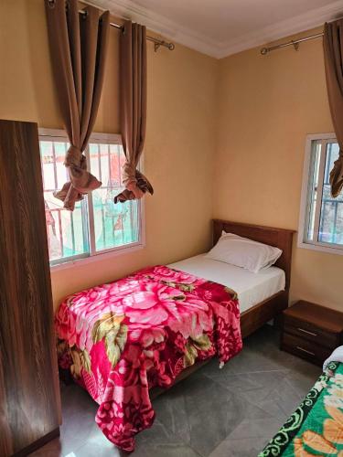 a bedroom with a bed and two windows at Kaira kunda guesthouse in Nimsat