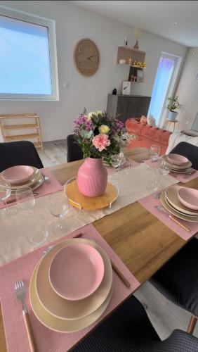 a dining room table with pink plates and a vase with flowers at Gîte duplex les Glycines in Bennwihr