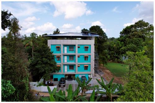 an apartment building with blue windows and trees at Vajra Periyar Heritage in Alwaye