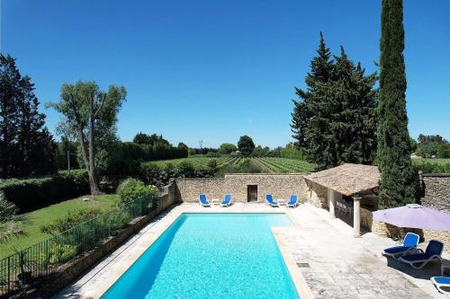 - une piscine dans une villa avec 2 chaises bleues dans l'établissement Provencal Farm with swimming pool near Isle sur la Sorgue - 10 people., à Les Vignères