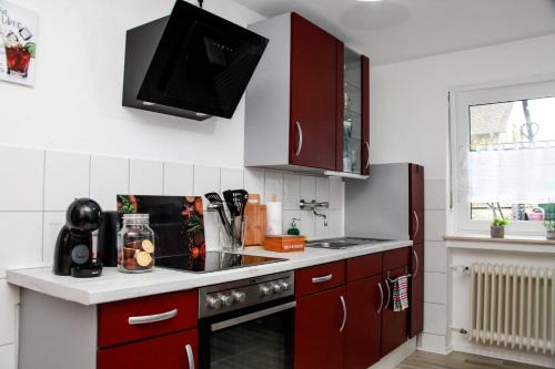 una cucina con armadi rossi e un piano cottura. di INDIVIDUAL APARTMENTS - Zentrale, ruhige Wohnung in Innenstadt - Küche, Parkplatz, Terrasse, SmartTV, Netflix a Bitburg