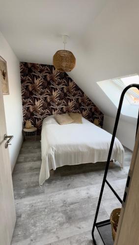a bedroom with a white bed and a wall at Gîte duplex les Glycines in Bennwihr